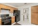 Spacious kitchen with black appliances and wood cabinets adjacent to a laundry area at 8921 Signal Terrace Dr, Las Vegas, NV 89134