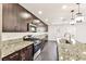 Modern kitchen features dark wood cabinets, stainless steel appliances, granite countertops, and pendant lighting at 9050 W Tropicana Ave # 1075, Las Vegas, NV 89147