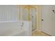 Bathroom with a tub, glass enclosed shower, and tiled walls, offering a clean and bright bathing experience at 9398 Sailing Water Ave, Las Vegas, NV 89147