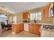 Well-lit kitchen featuring wooden cabinetry, granite countertops and a dining table with seating under an elegant chandelier at 9398 Sailing Water Ave, Las Vegas, NV 89147