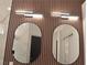 Modern bathroom featuring round mirrors and contemporary light fixtures over a wood paneled wall at 9604 Flying Eagle Ln, Las Vegas, NV 89123