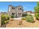 A serene backyard featuring a patio, rock landscaping, and lush green bushes under a clear blue sky at 9748 Derbyhill Cir, Las Vegas, NV 89117