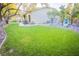 Large backyard with a well-kept lawn, trees, a paved patio, and rock landscaping at 10391 Avebury Manor Ln, Las Vegas, NV 89135