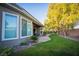 The backyard has large windows, a patio with seating, and a green lawn with mature trees at 10391 Avebury Manor Ln, Las Vegas, NV 89135