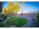 A lush backyard with green grass, trees, plants and landscaping bordering the lawn at 10391 Avebury Manor Ln, Las Vegas, NV 89135