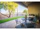 Covered patio with table, chairs, grill, manicured lawn and mature tree at 10391 Avebury Manor Ln, Las Vegas, NV 89135