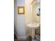 Charming powder room featuring a pedestal sink, gold framed mirror, and modern gray flooring at 10391 Avebury Manor Ln, Las Vegas, NV 89135