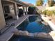Inviting backyard pool with rock features, patio seating, and lush landscaping for outdoor relaxation at 10548 Ettenmoor Ave, Las Vegas, NV 89135