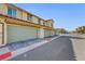 Exterior view of multiple beige garages with dark trim and stone paver driveways at 1125 Meadow Sparrow Pl, Henderson, NV 89011