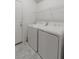 Functional laundry room with a white washer and dryer set, tiled flooring, and a storage shelf at 1145 Belton Lake Ave, North Las Vegas, NV 89086