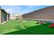 Wide backyard featuring an artificial grass lawn, multiple play structures, and enclosed perimeter at 1297 Ventura Cliffs Ave, Henderson, NV 89012