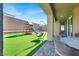 Backyard featuring synthetic grass, playground, hanging chair and a covered dining area at 1297 Ventura Cliffs Ave, Henderson, NV 89012