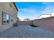 Gravel backyard with a small patch of grass, brick wall, and view of neighboring houses at 1297 Ventura Cliffs Ave, Henderson, NV 89012