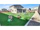 Large backyard featuring an artificial grass lawn and various play structures and toys at 1297 Ventura Cliffs Ave, Henderson, NV 89012