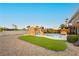 Manicured backyard featuring a pool with rock waterfall, artificial turf and rock landscaping at 200 E Desert Rose Dr, Henderson, NV 89015