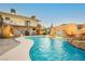 Beautiful backyard pool featuring a rock waterfall, grotto, and adjacent lounge area with a hanging chair at 200 E Desert Rose Dr, Henderson, NV 89015