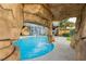 Tranquil backyard pool view from inside the rock waterfall grotto with seating and lounge area at 200 E Desert Rose Dr, Henderson, NV 89015
