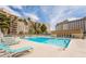 Community swimming pool with lounge chairs surrounded by palm trees and buildings at 205 E Harmon Ave # 112, Las Vegas, NV 89169