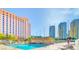 Community swimming pool and lounge chairs surrounded by high-rise buildings and golf course at 205 E Harmon Ave # 112, Las Vegas, NV 89169