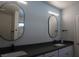 Modern bathroom with dual sinks, black faucets, and oval mirrors with sconces at 2874 Tori Way, Henderson, NV 89074