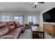 Bright living room with a leather sofa, ceiling fan, and view of the backyard at 387 Larksong Ave, Henderson, NV 89011