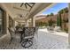 Covered outdoor patio with an elaborate dining set overlooking a lush backyard and serene hillside views at 4220 San Alivia Ct, Las Vegas, NV 89141