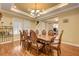 Formal dining room featuring a decorative light fixture, tray ceiling, and wood floors at 4260 Helena Cove Ct, Las Vegas, NV 89129
