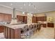 A gourmet kitchen boasts a large granite island and stainless appliances with barstool seating and custom cabinetry at 4260 Helena Cove Ct, Las Vegas, NV 89129