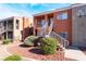 Exterior view of a red stucco condo building with white stairs and landscaping at 4730 E Craig Rd # 1115, Las Vegas, NV 89115