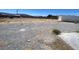 Spacious backyard featuring gravel, outbuildings, partial concrete slab, and scenic mountain views at 4910 Elizabeth St, Pahrump, NV 89048