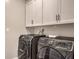 Convenient laundry room featuring front loading washer and dryer with storage cabinets at 5429 Blinding Lights St, North Las Vegas, NV 89081