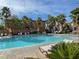 Inviting community pool area with palm trees, lounge chairs, umbrellas, and greenery at 6255 W Arby Ave # 239, Las Vegas, NV 89118