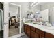 Bright bathroom featuring dual sinks, dark wood cabinetry, and a large mirror with views into the adjacent bedroom at 7301 Heggie Ave, Las Vegas, NV 89131