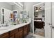 Bright bathroom featuring dual sinks, dark wood cabinetry, and a large mirror with views into the adjacent bedroom at 7301 Heggie Ave, Las Vegas, NV 89131