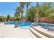 Backyard swimming pool and spa surrounded by mature trees and an array of potted plants at 7301 Heggie Ave, Las Vegas, NV 89131