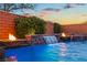 Inviting backyard oasis with a sparkling pool, brick wall, fire bowls, and lush greenery at 7322 Columbia Rock Ct, Las Vegas, NV 89178