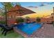 Backyard boasts a shimmering pool, brick patio, sun umbrella, fire bowls, and lush greenery at 7322 Columbia Rock Ct, Las Vegas, NV 89178