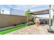 This backyard features a covered patio area, artificial grass, and a brick fence at 8021 Adelaide Hills St, Las Vegas, NV 89113