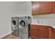 Laundry room with front loading washer and dryer and a utility sink with wood cabinets at 8405 Canyon Crevasse St, Las Vegas, NV 89166
