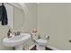 Stylish half-bathroom featuring a pedestal sink, modern fixtures and neutral colors at 8405 Canyon Crevasse St, Las Vegas, NV 89166