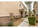 Close up of the tan siding of a townhouse with gravel landscaping and a sidewalk at 8675 Traveling Breeze Ave # 101, Las Vegas, NV 89178