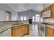 Open kitchen featuring wooden cabinets, granite countertops, and stainless steel appliances with view to the living room at 8675 Traveling Breeze Ave # 101, Las Vegas, NV 89178
