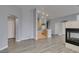 Open-plan living room with fireplace and wood-look floors, connecting to kitchen and hallway at 8675 Traveling Breeze Ave # 101, Las Vegas, NV 89178