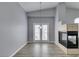 Open-concept living room with vaulted ceilings, a modern fireplace, and doors to the outside at 8675 Traveling Breeze Ave # 101, Las Vegas, NV 89178
