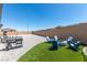 Backyard with an artificial grass area, fire pit, BBQ, and desert landscaping at 8929 Cassia Winds St, Las Vegas, NV 89166