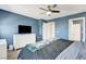 Comfortable bedroom with a ceiling fan, blue accent wall, and a white dresser with a TV at 9065 Adorable Ave, Las Vegas, NV 89149