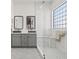 Well-lit bathroom featuring double sinks, sleek gray cabinetry and a shower with glass block window at 9096 Nomo St, Las Vegas, NV 89123