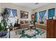 Cozy living room featuring traditional furnishings, decorative rug, and bright natural light from large windows at 9096 Nomo St, Las Vegas, NV 89123