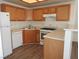 Functional kitchen featuring wood cabinets, white appliances, and a peninsula at 9470 Peace Way # 112, Las Vegas, NV 89147