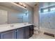 Bathroom features double vanity with grey cabinets, large mirror, shower/tub combination, and tiled floors at 9780 Ziegler Ave, Las Vegas, NV 89148